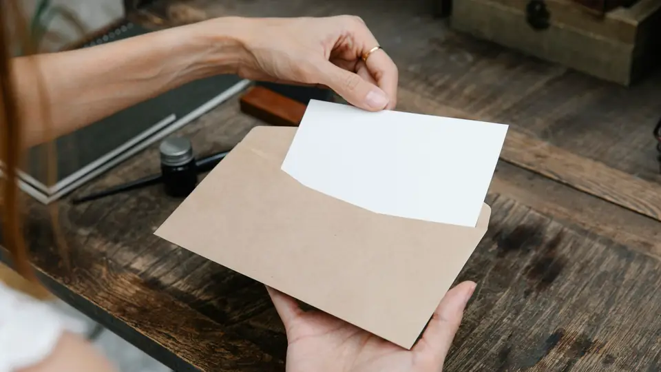 Hands holding a blank card above a paper envelope