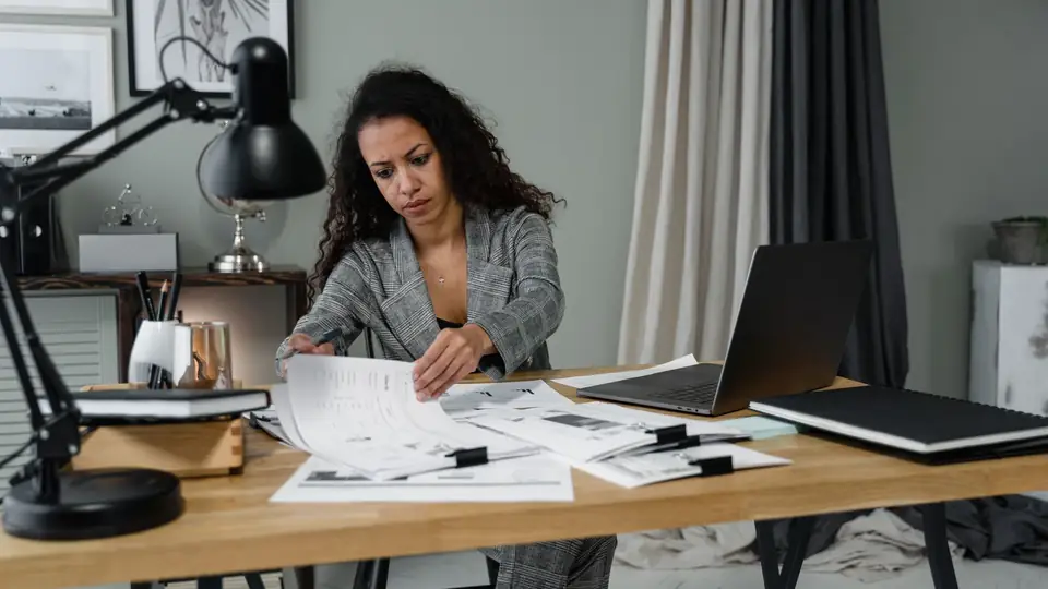 Business owner reviewing paperwork beside a laptop